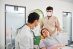 Dr. Kamyab Banitorfi untersucht einen Patienten im Behandlungsstuhl während einer zahnärztlichen Kontrolluntersuchung.