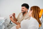 Ein Patient liegt im Behandlungsstuhl, während eine Mitarbeiterin des Dentalogicum eine professionelle Zahnreinigung durchführt.